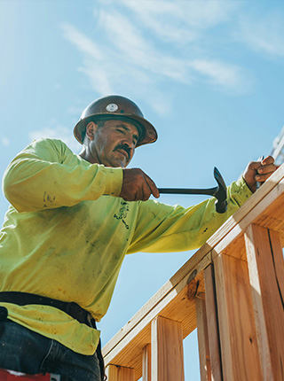 Charpentier clouant une ossature bois sur chantier