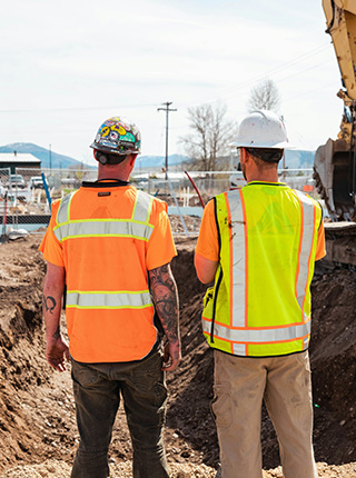 Deux terrassiers supervisant une pelleteuse sur chantier